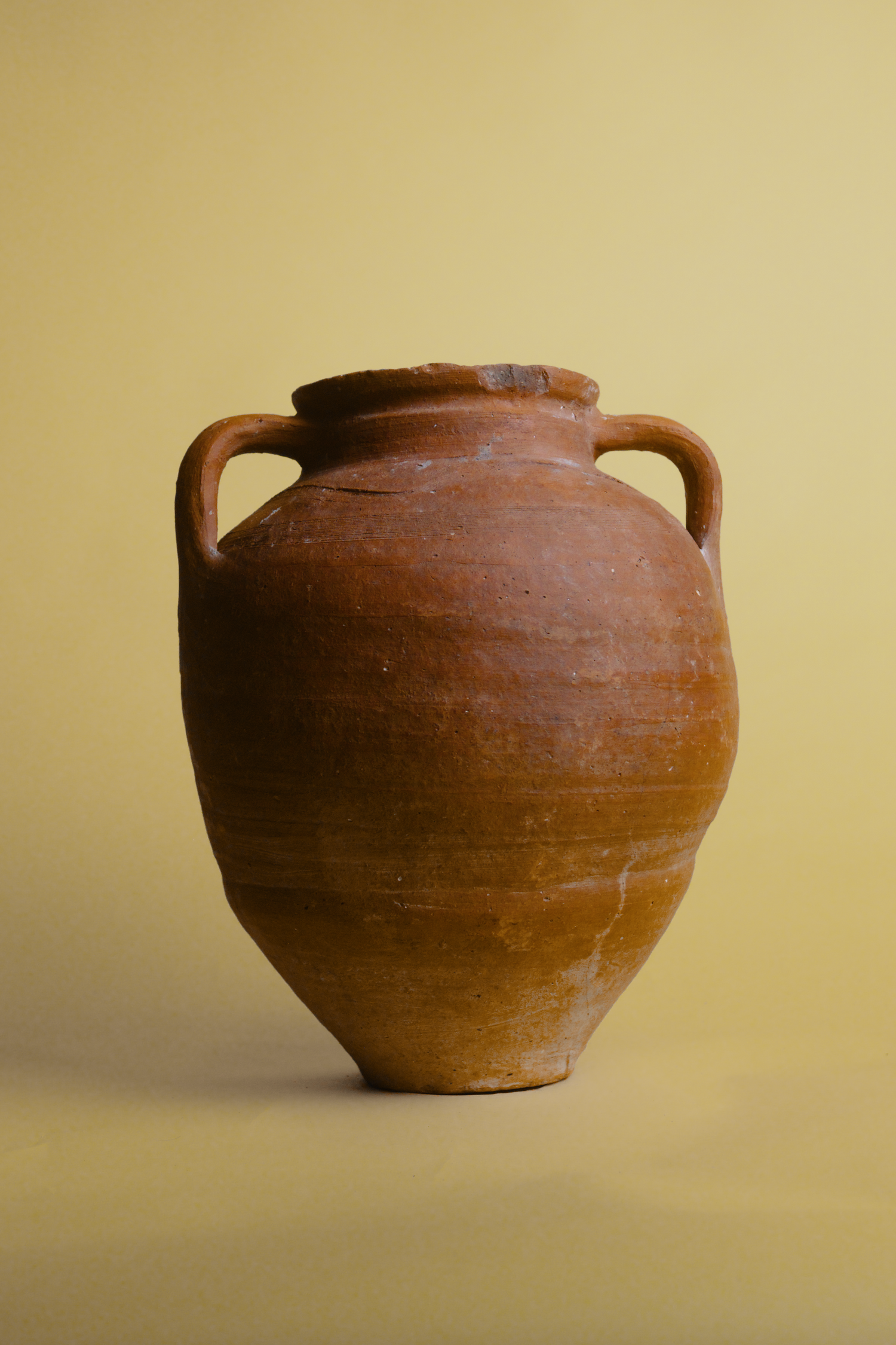 Handmade vintage Turkish clay pot with dual handles, featuring a rich terracotta finish and rustic texture, photographed on a soft yellow background. Perfect for adding timeless charm to home décor or tablescapes