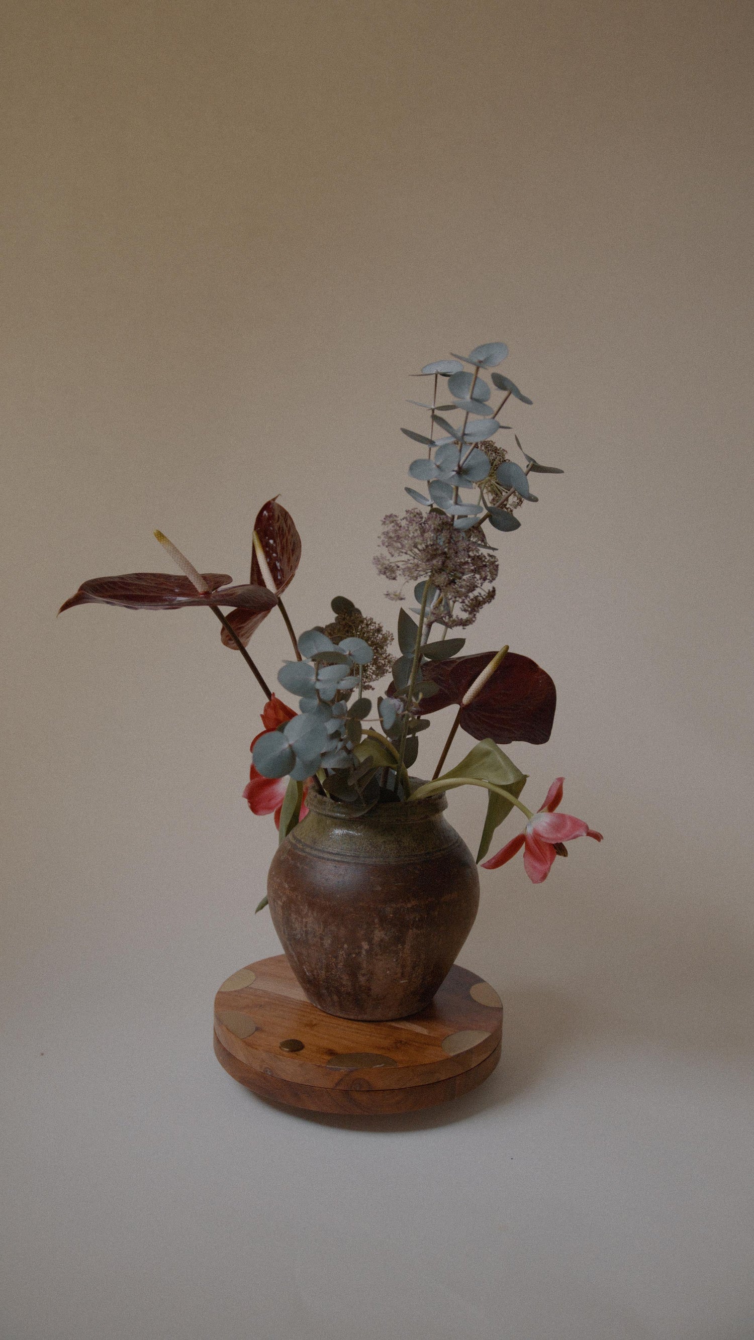 Handmade vintage Turkish clay pot with a rich patina, styled with a vibrant floral arrangement of eucalyptus, anthuriums, and tulips.