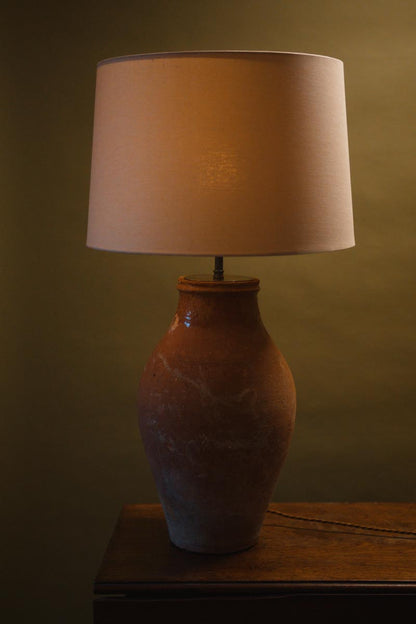 Rustic terracotta table lamp with a vintage pottery base and warm light linen shade, adding cozy charm to modern farmhouse or eclectic spaces